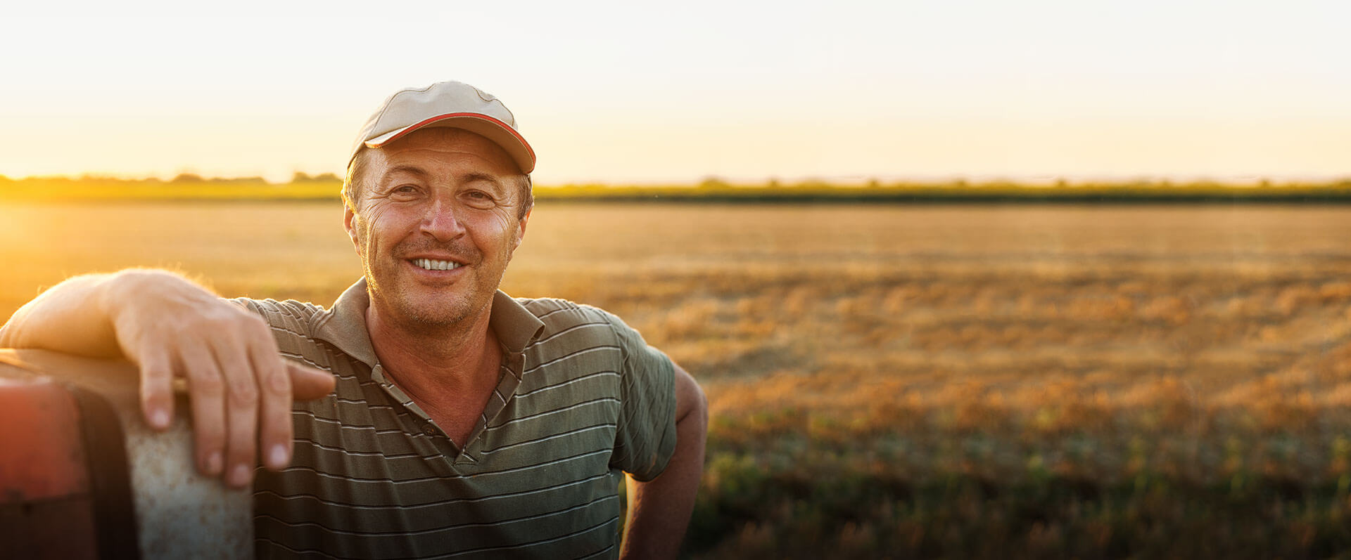 Image of Farmer Leaning on a truck in a field at sunset